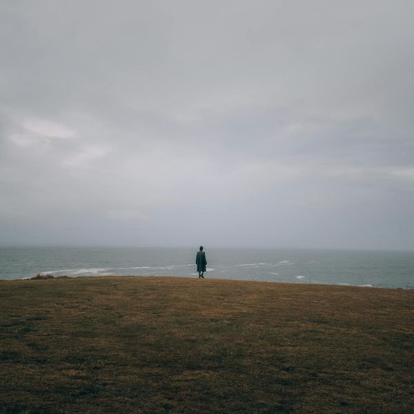 Person meditating peacefully in a calm, dark environment.